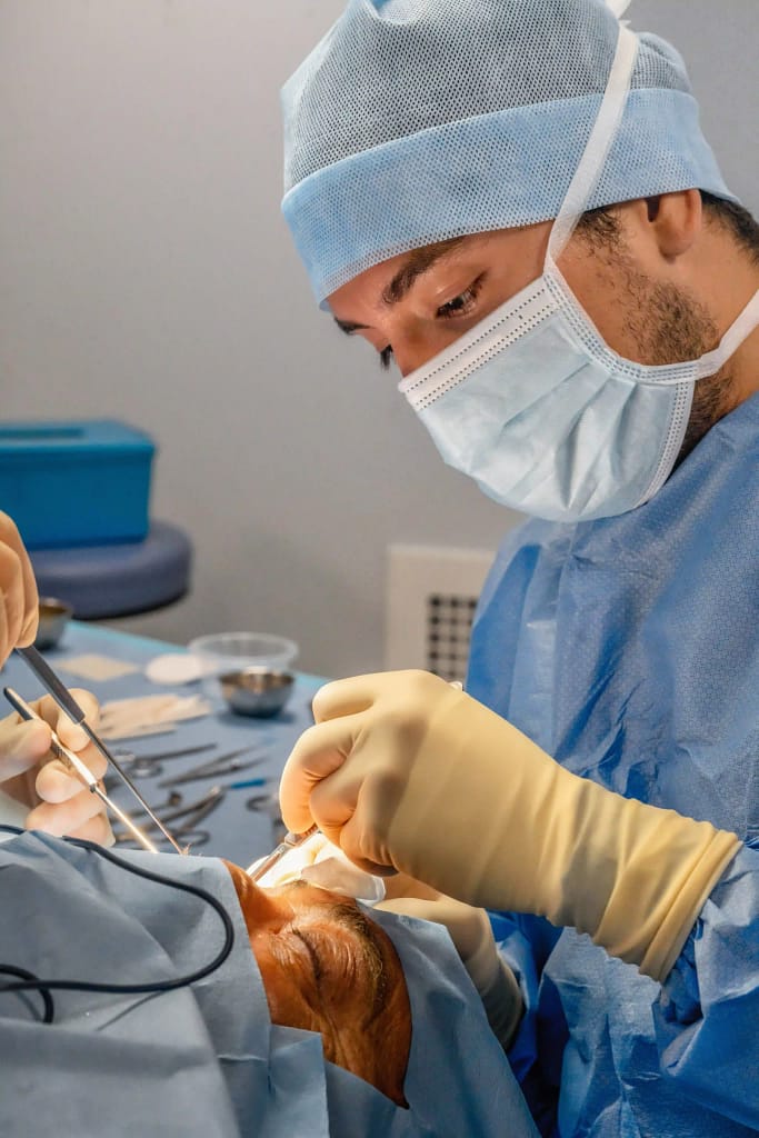 Dr Mauricio Pinto en salle d’opération, réalisant une chirurgie ophtalmologique au bloc opératoire.